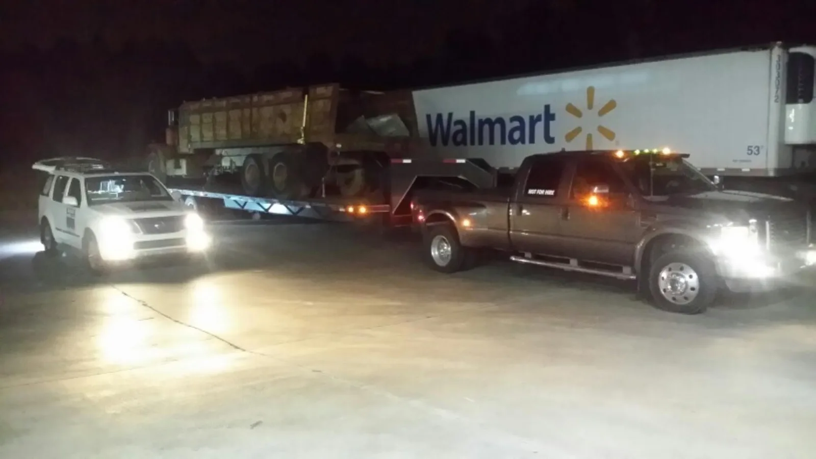 A commercial box truck receiving roadside tire service at night.